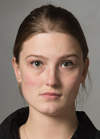 Head shot of young woman with her hair tied back on a grey background