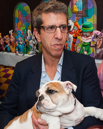 Jason Flom, CEO Lava Records holding pet dog in front of painting of cartoon characters.