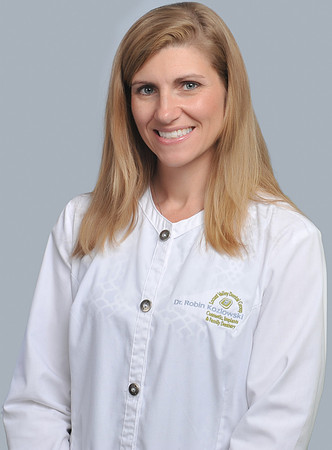 Portrait of Dr. Robin Kozlowski wearing white lab coat in front of light blue background.