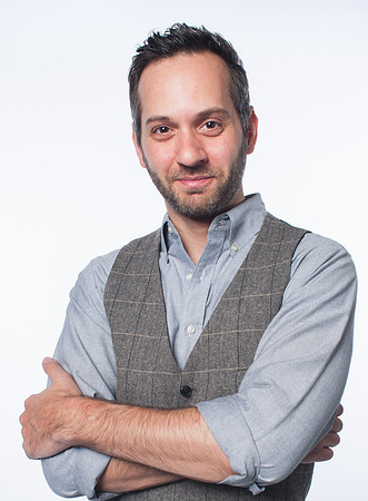 Portrait of young man wearing a vest while crossing his arms on a white background