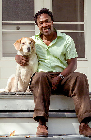 Academy Award winning Director Roger Williams sitting on the stairs of hi porch holding his dog Sadie
