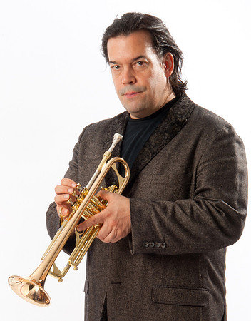 Portrait of Mac Golahan, Band Leader, holding trumpet standing in front of  a white background