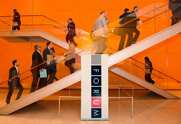 Two stairways forming an X with people climbing stairs, orange wall