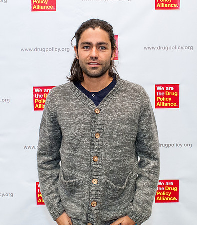 Actor Adrian Grenier standing in front of banner.