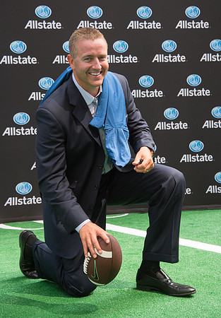 Kirk Herbstreit kneeling holding football at event.