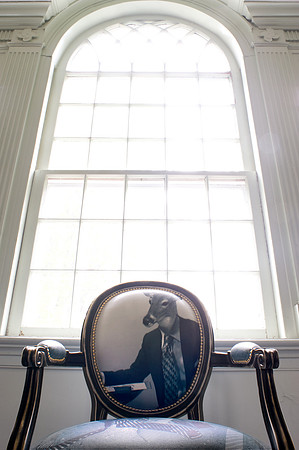 Back of chair with print of a deer in a suit, large window behind.