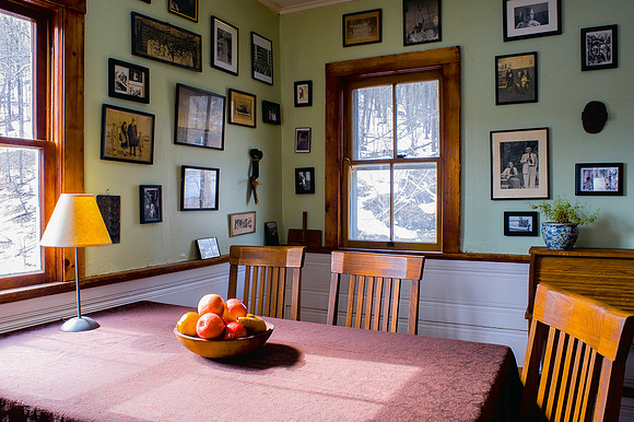 Farmhouse kitchen table and chairs with various small framed photos on wall.