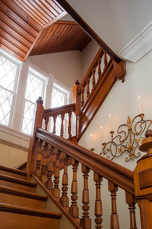 looking up ornate stairway with candelabra on wall and leaded windows