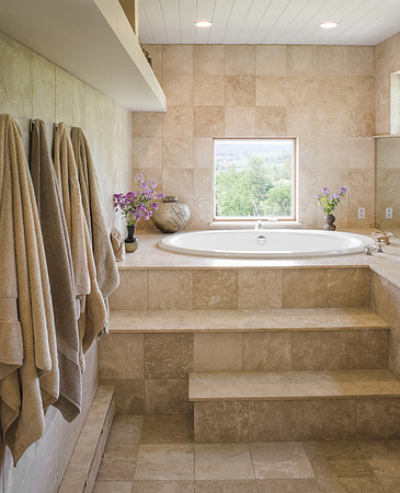 Contemporary bathroom with tan marble and a square window. Towels hanging on peg to the left
